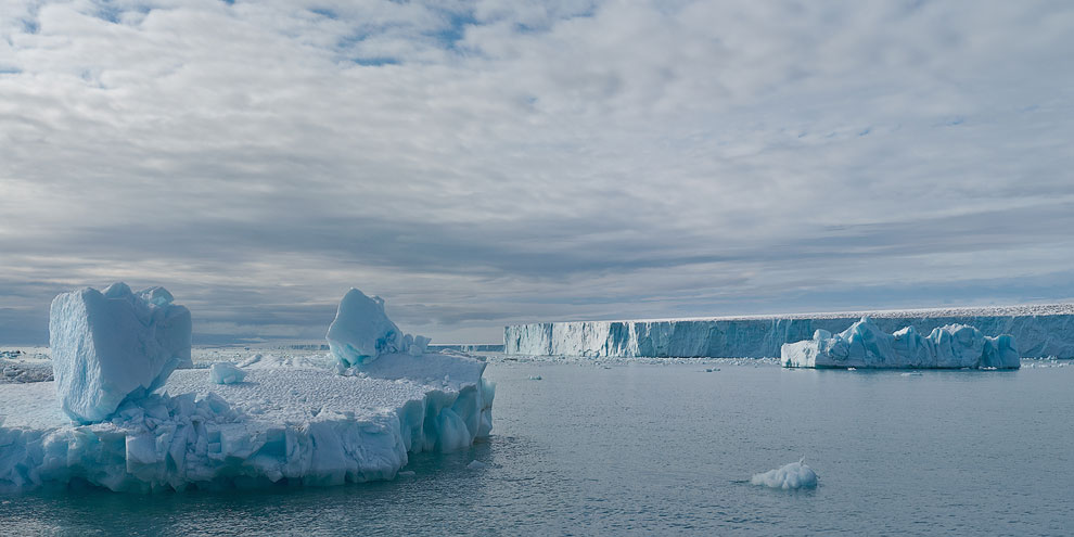 Icebergs with Austfonna Glacier on the background. Austfonna Ice Cap, Nordaustlandet Island, Svalbard (Spitsbergen) Archipelago, Norway.