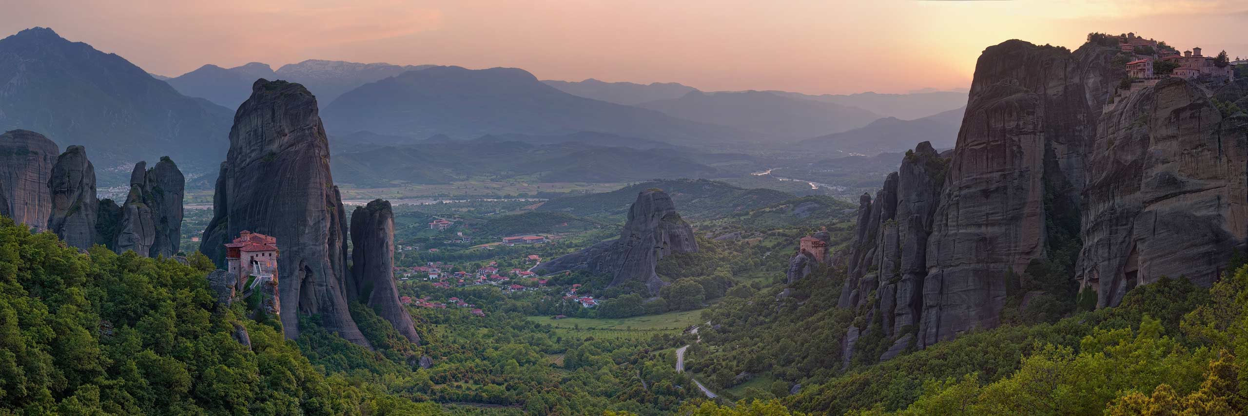 Roussanou and St. Nicholas Anapafsas Monasteries with town of Kastraki on Thessaly valley floor at sunset. Meteora, Greece