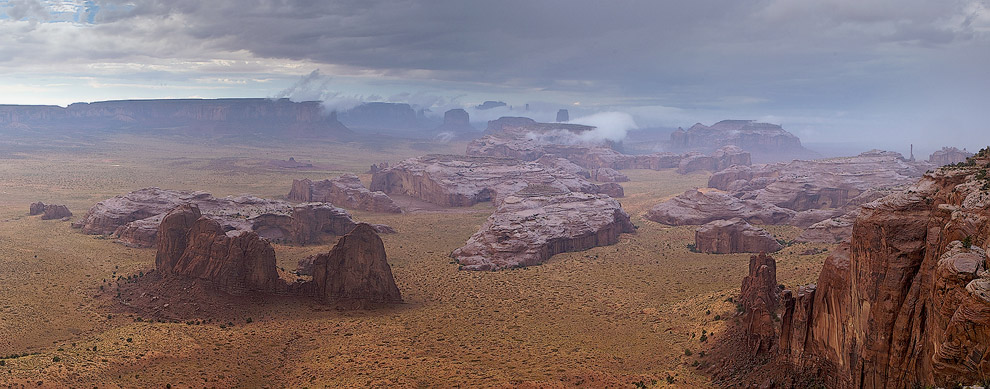 Fog rising up from the hot monoliths under the rain. Tom's Point, Hunts Mesa, Monument Valley, Arizona, USA. Panoramic. - Monument-Valley-Agathla-Peak-El-Capitan-Owl-Church-Rock - Mike Reyfman Photography
