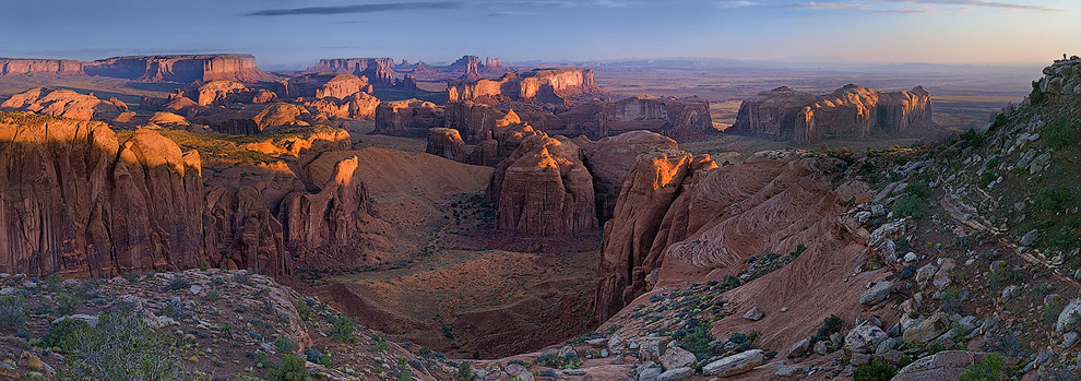 Photographer on the cliff over Monument Valley at sunrise. Hunts Mesa, Monument Valley, Arizona, USA. Panoramic. - Monument-Valley-Agathla-Peak-El-Capitan-Owl-Church-Rock - Mike Reyfman Photography