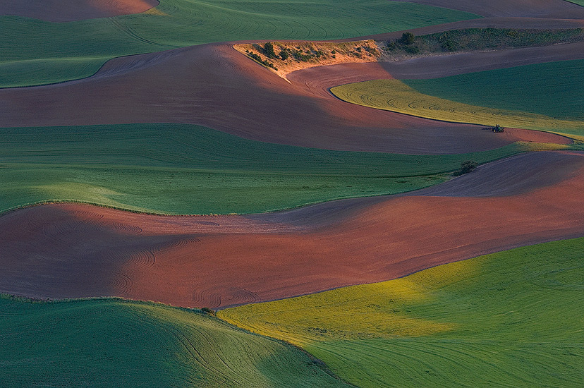 Tractor rests in the field of the Palouse at sunset. Steptoe Butte, Palouse, Washington, USA.