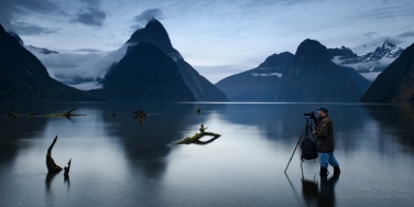 Frozen.-Photographer-taking-photos-of-Milford-Sound-at-Low-tide.-Milford-Sound,-Fiordland-National-Park,-New-Zealand.